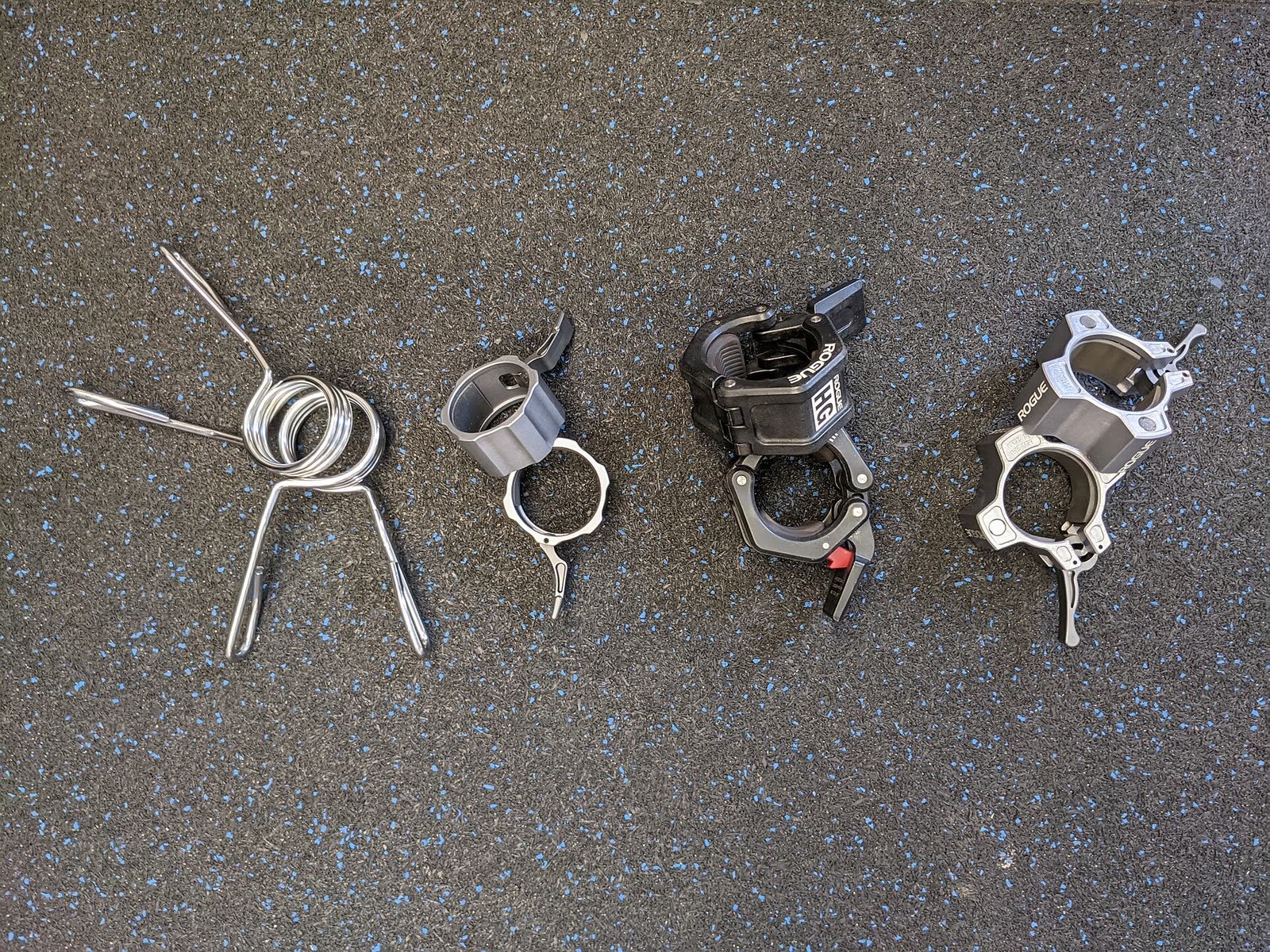 Four types of barbell collar laid out on rubber flooring